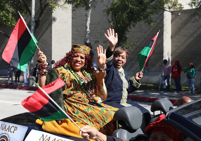 Two women waving Pan-African flags from a car during the Black Parade and Festival.
