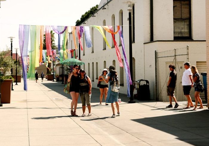 Friends pose for a picture under colorful rainbow banners in Pasadena.