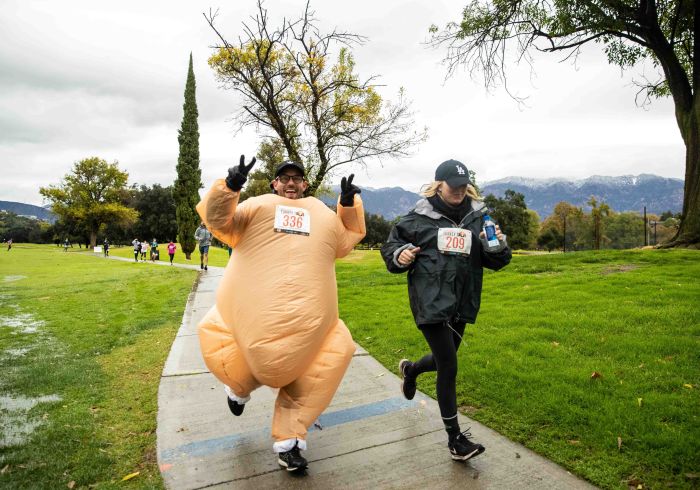 Two competitors run along a path during the Turkey Trot. One runner is dressed in an inflated turkey costume